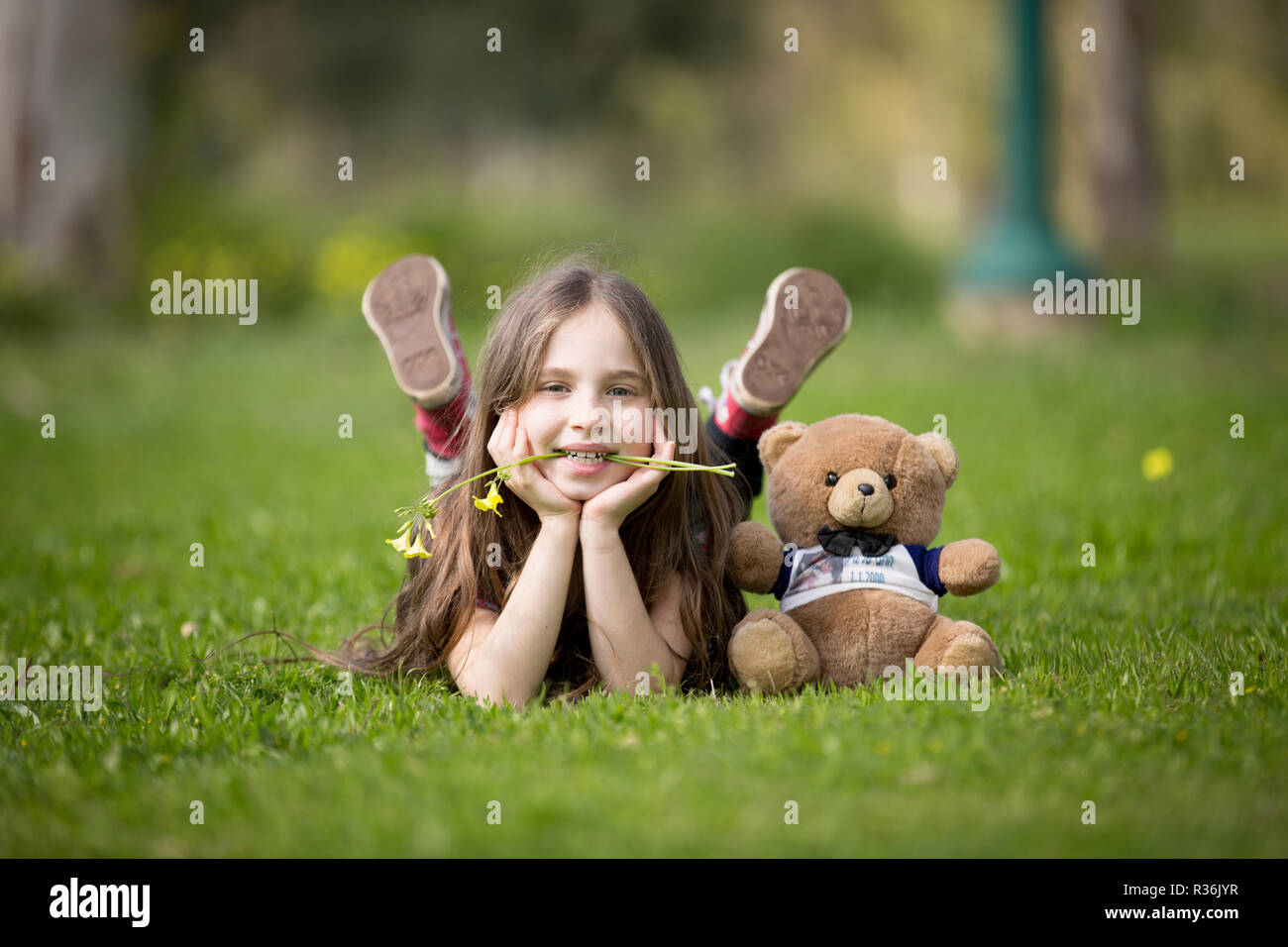 Lächelnde Mädchen im Park mit Teddybär Stockfoto