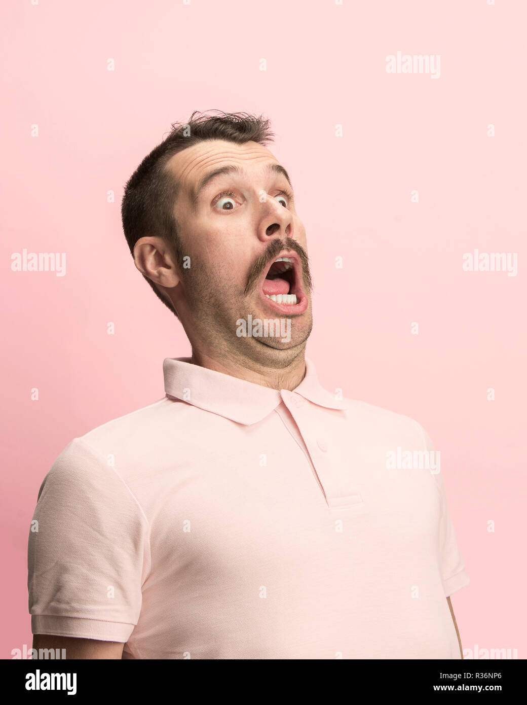 Das überrascht und erstaunt junge Mann schreiend mit offenen Mund auf rosa Hintergrund isoliert. Konzept der Schock Gesicht emotion Stockfoto