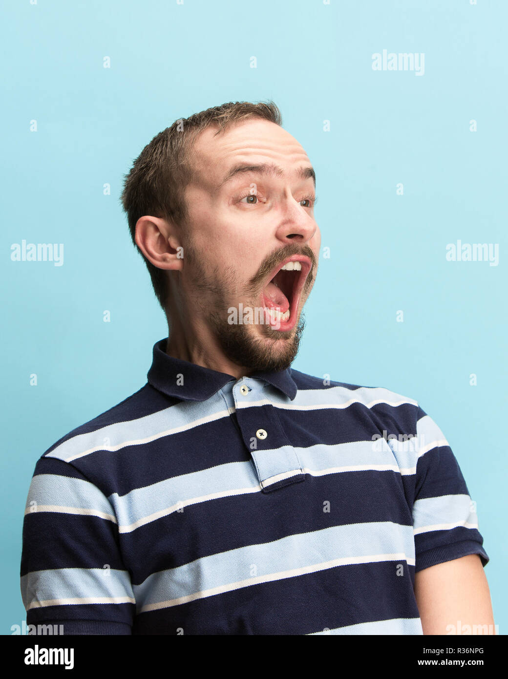Das überrascht und erstaunt junge Mann schreiend mit offenen Mund auf blauem Hintergrund isoliert. Konzept der Schock Gesicht emotion Stockfoto