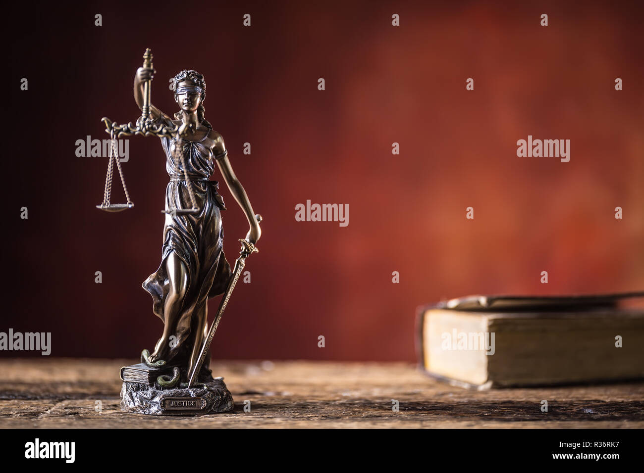 Lady "Justicia mit Schwert und Waage Bronze Figur mit Buch auf dem Holztisch. Stockfoto