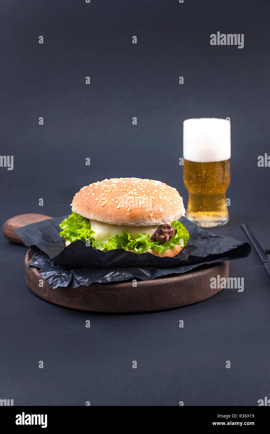 Große Hamburger, Bier und Notebook für die Planung auf einem schwarzen Hintergrund. Fast Food und Snacks. Freier Platz für Text. Flach. Platz kopieren Stockfoto