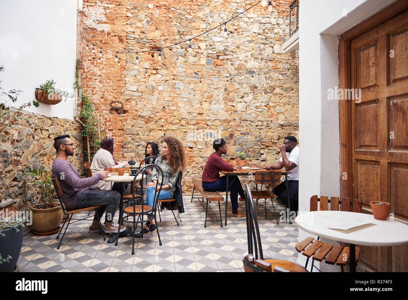 Diverse Jugendliche über Kaffee in einem Cafe Hof chatten Stockfoto