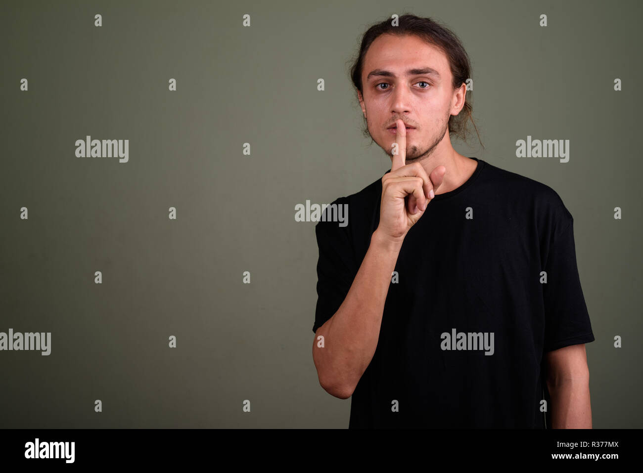 Junger stattlicher Mann mit schwarzen Hemd gegen Farbige backgroun Stockfoto