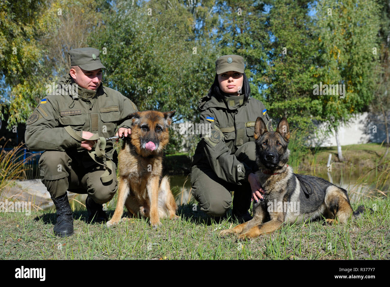 Am Eckzahn entfernt. Militärische Handler und Service Hunde sitzen auf einem Boden nach der Ausbildung. Oktober 18, 2018. Novo-Petrivtsi Militärbasis, Ukraine Stockfoto