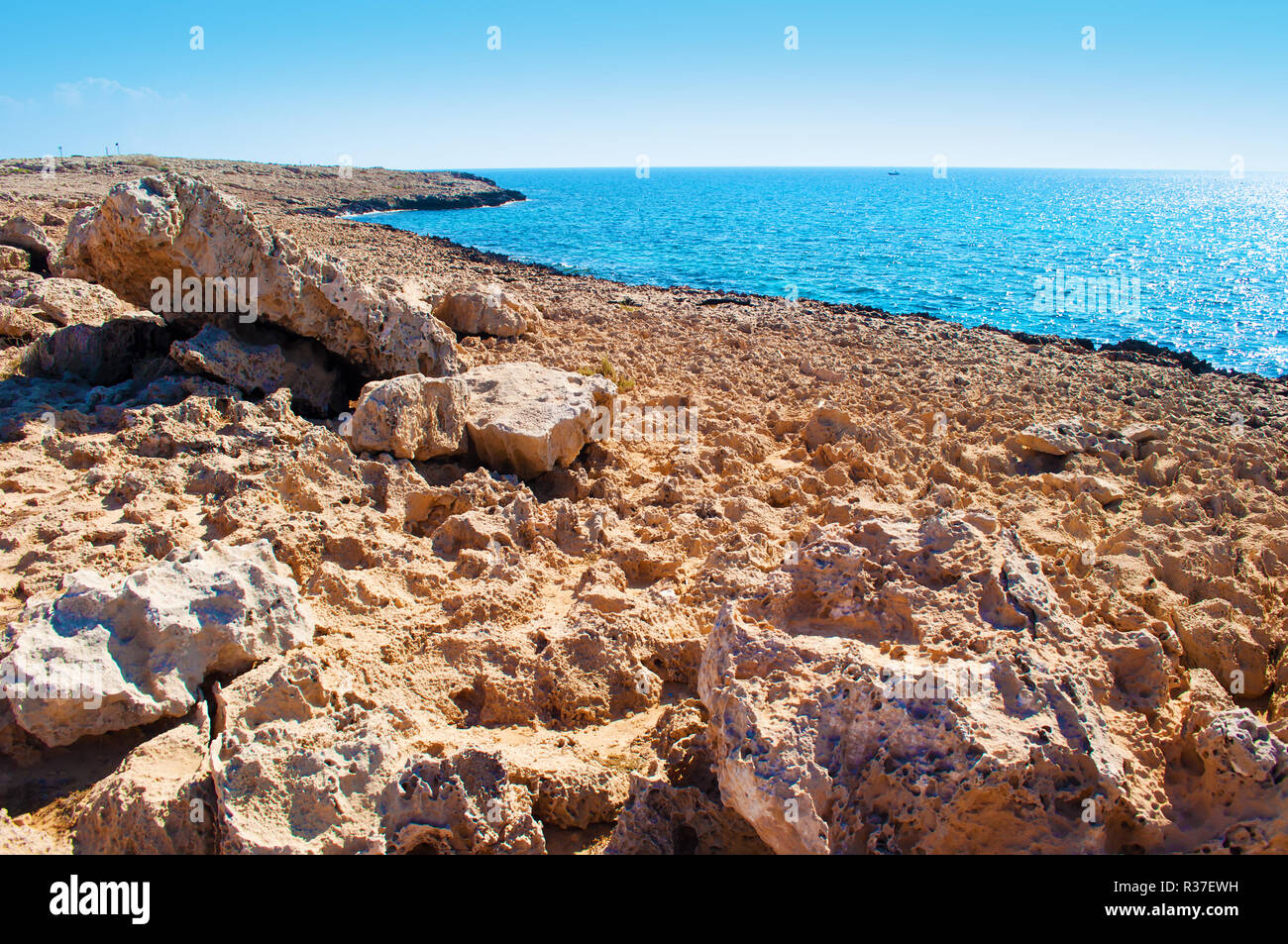 Bild einer Marslandschaft in der Nähe von Agia Napa, Zypern. Grobe Kalkstein Küste mit riesige Felsbrocken in der Nähe von Deep Blue ruhiges Wasser im Hintergrund. Herzlichen da Stockfoto