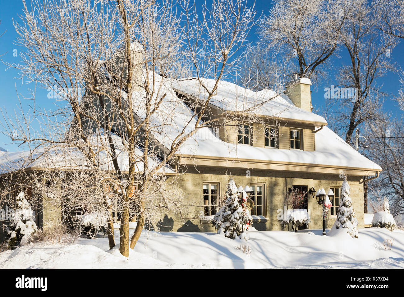 Alte 1840s Home Fassade mit grauen Stein Mauerwerk und Holz Verschalungen plus Weihnachtsschmuck im Winter, Quebec, Kanada Stockfoto