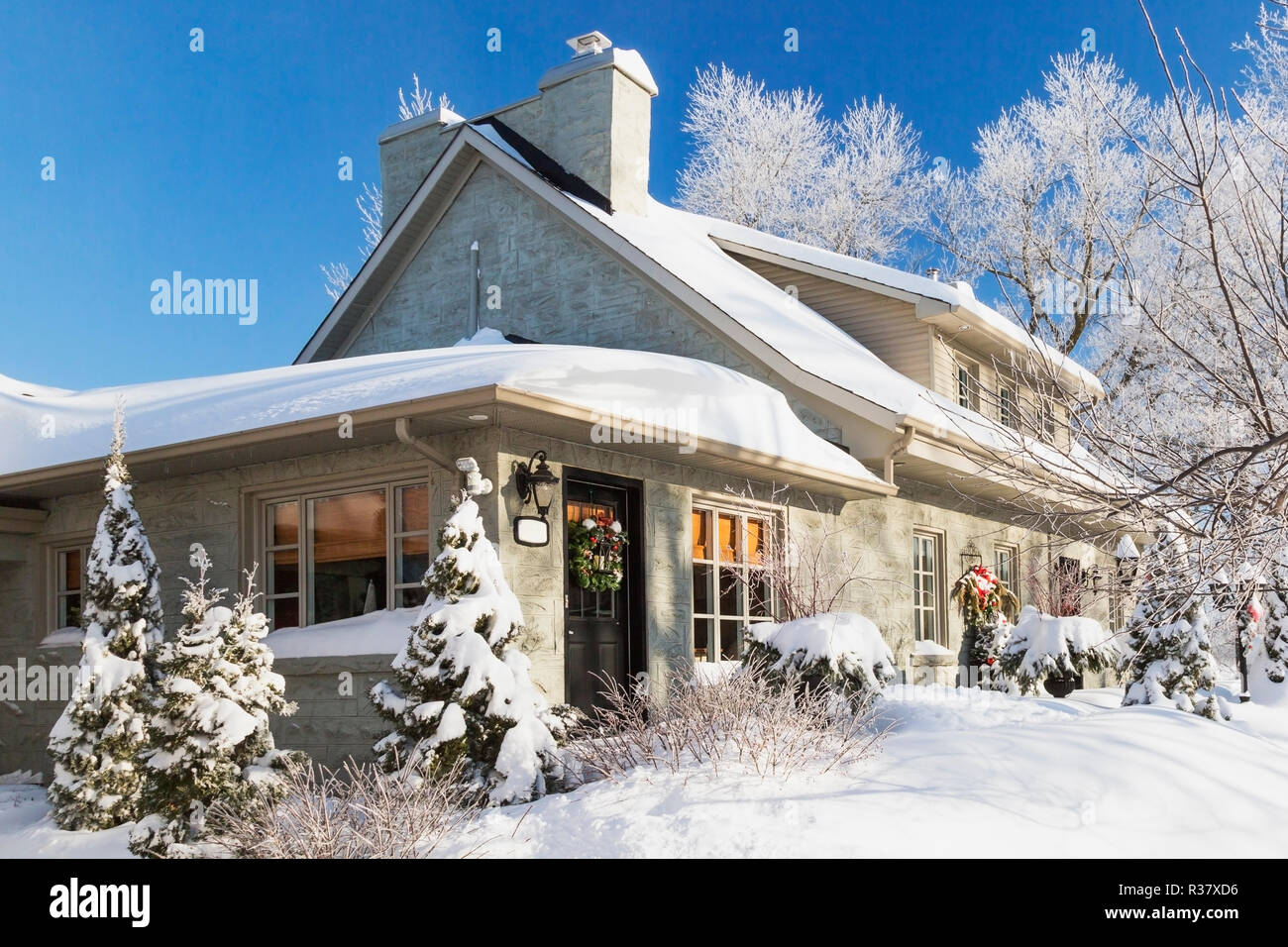Alte 1840s Home Fassade mit grauen Stein Mauerwerk und Holz Verschalungen plus Weihnachtsschmuck im Winter, Quebec, Kanada Stockfoto