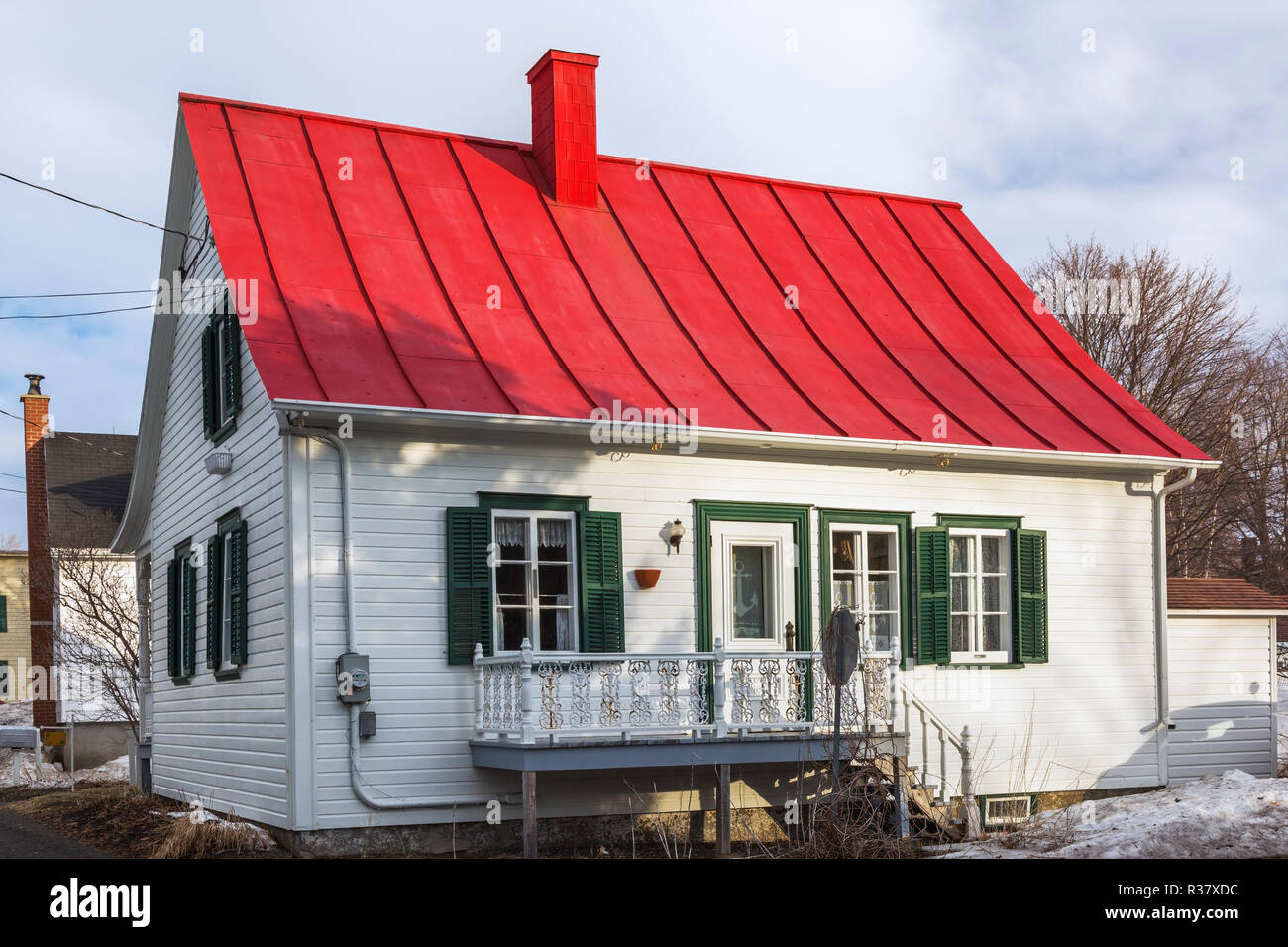 Rückseite des Alten 1835 weißes Holz Plank mit grünen Canadiana Landhausstil Haus mit roten Blech Dach im Frühjahr Stockfoto