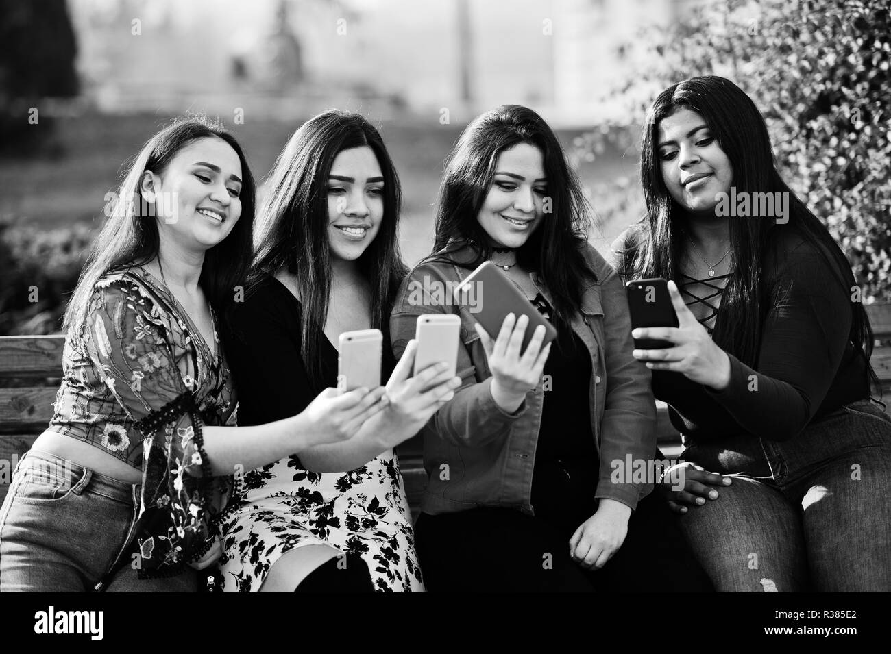Gruppe von vier glücklich und ziemlich latino Girls aus Ecuador stellte auf der Straße und auf Mobiltelefone. Stockfoto