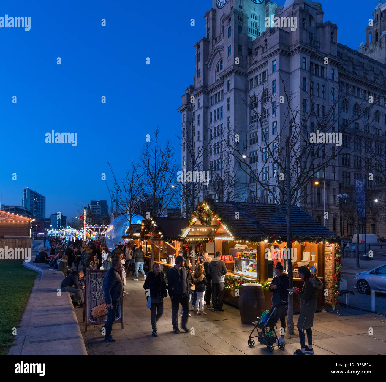 Weihnachtsmarkt Stände auf dem Weihnachtsmarkt Ice Festival Messegelände mit der Leber Gebäude hinter, Pier Head, Liverpool, England, UK Stockfoto