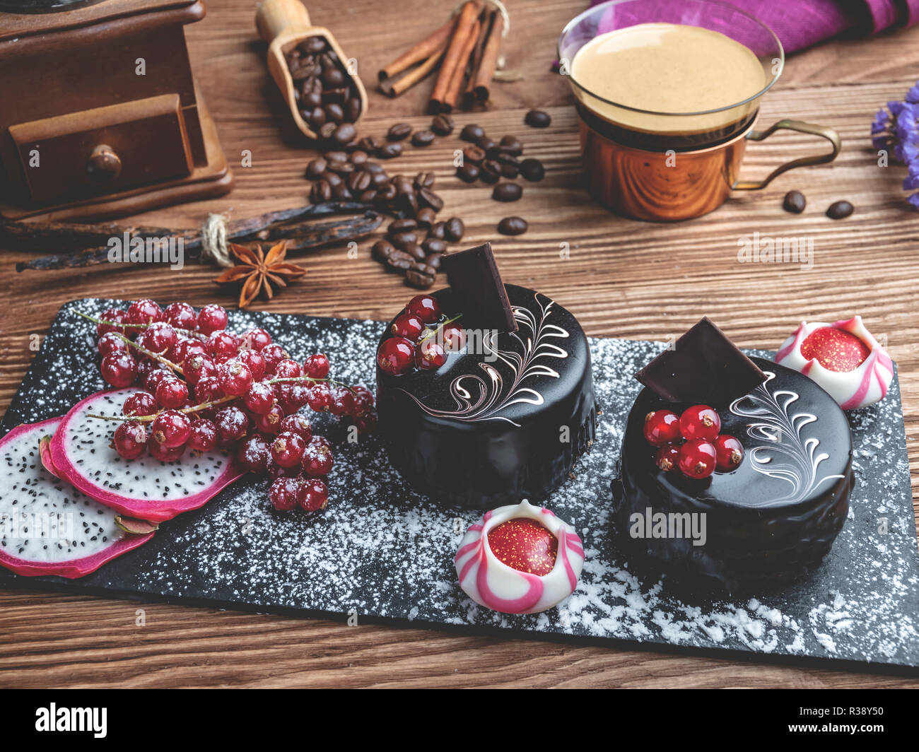 Schokoladenkuchen mit roten Johannisbeeren. Tasse Kaffee mit Dessert auf den Tisch Nahaufnahme Stockfoto