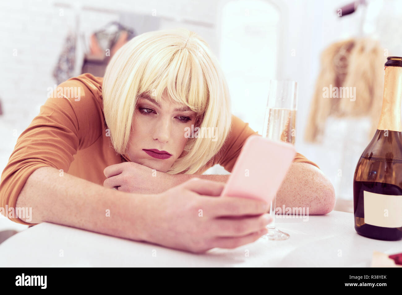 Attraktive crossdresser mit Auf sms mit seinem Smartphone Stockfoto