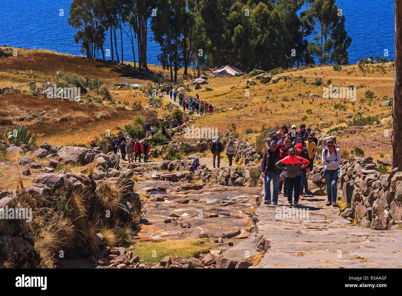 Gruppe von Touristen zu Fuß auf einem Felsen weg an der Insel Taquile, Puno, Peru Stockfoto