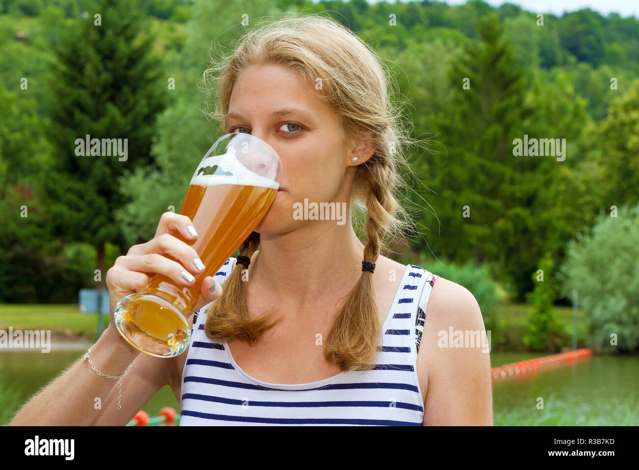 Junge Frau trinkt ein Bier Stockfoto