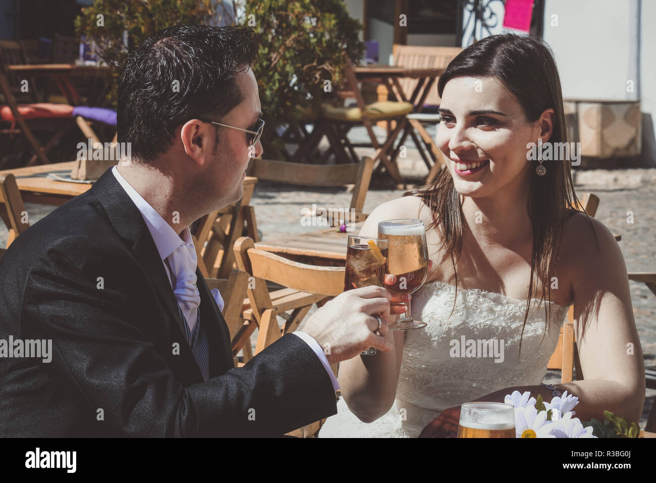 Junge Hochzeitspaar am Tag ihrer Hochzeit, entspannen Sie in der Bar und mit einem Bier Stockfoto