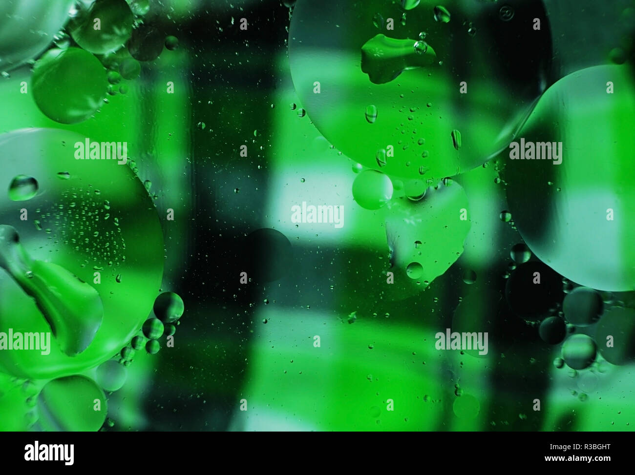 Ein wunderschönes und farbenfrohes Makro von Öl Blasen auf dem Wasser mit einem Plaid grüne und schwarze Textur als Hintergrund Stockfoto