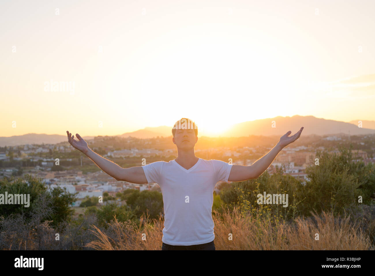 Junge Attraktive touristische Mann entspannt mit geschlossenen Augen und Arme in der Natur erhöht Stockfoto