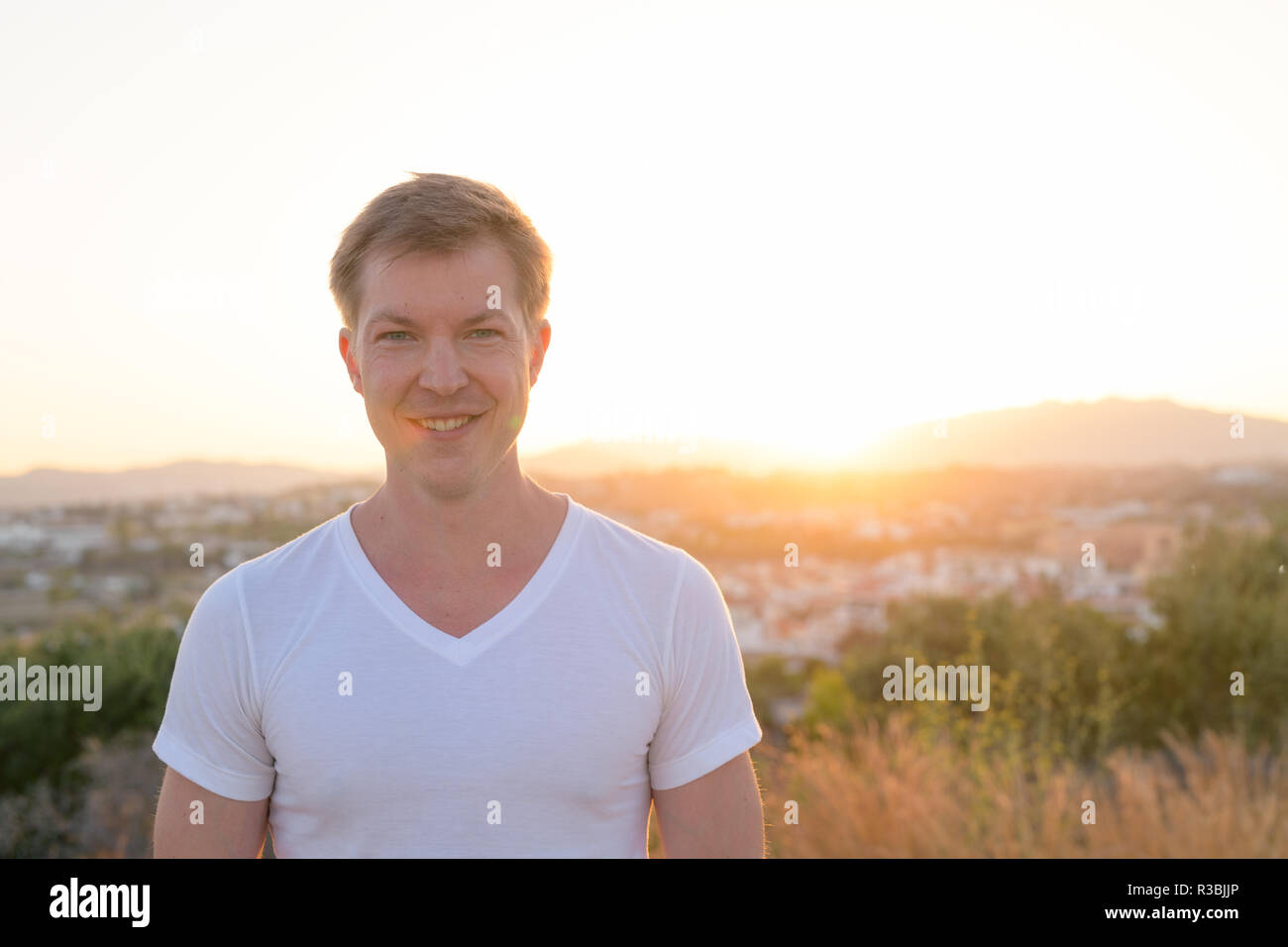 Junge Attraktive touristische Mann lächelnd gegen Sonnenlicht Stockfoto