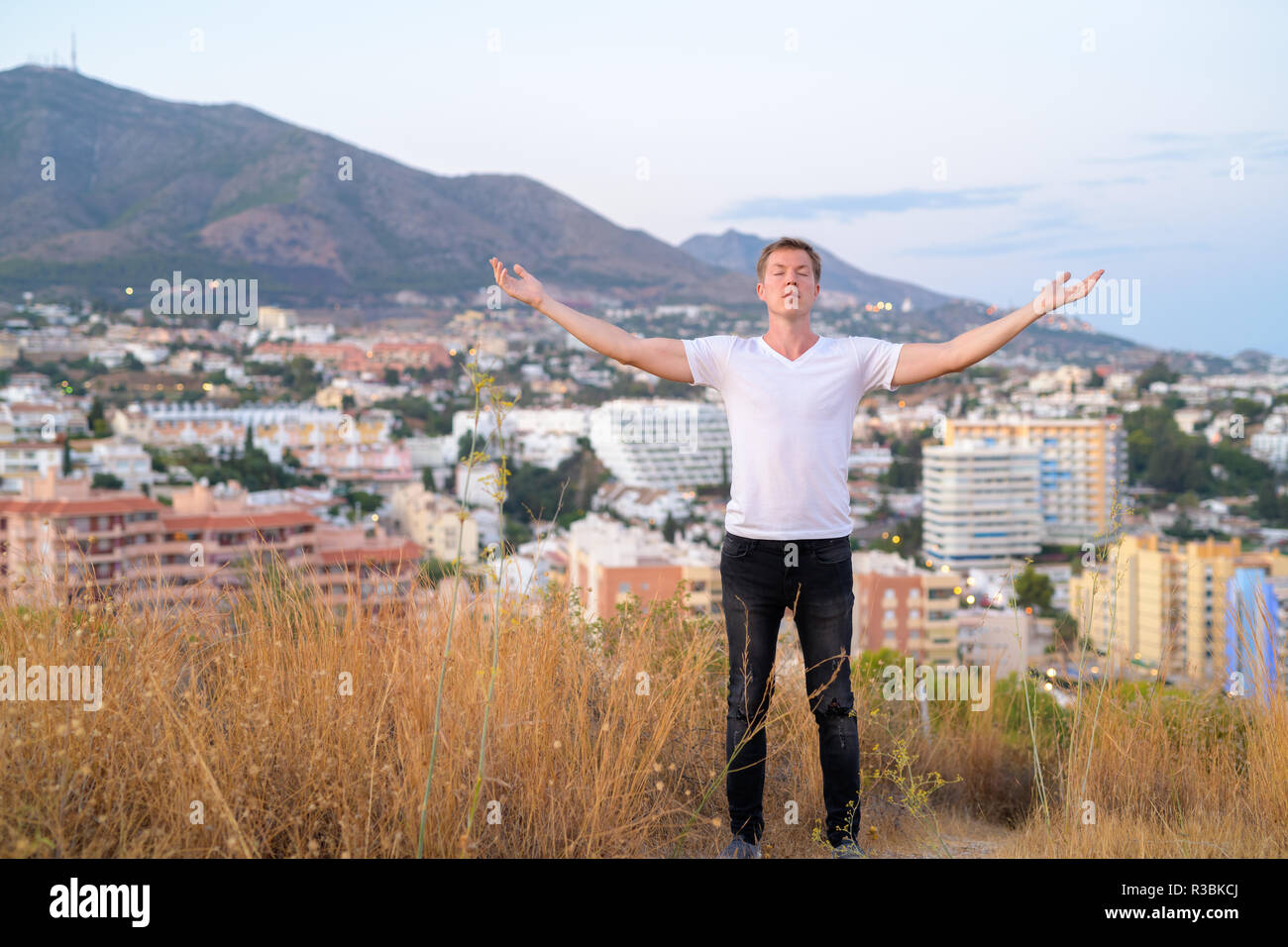 Junge touristische Mann Schließen der Augen beim Stehen mit offenen Armen auf der Spitze des Hügels Stockfoto