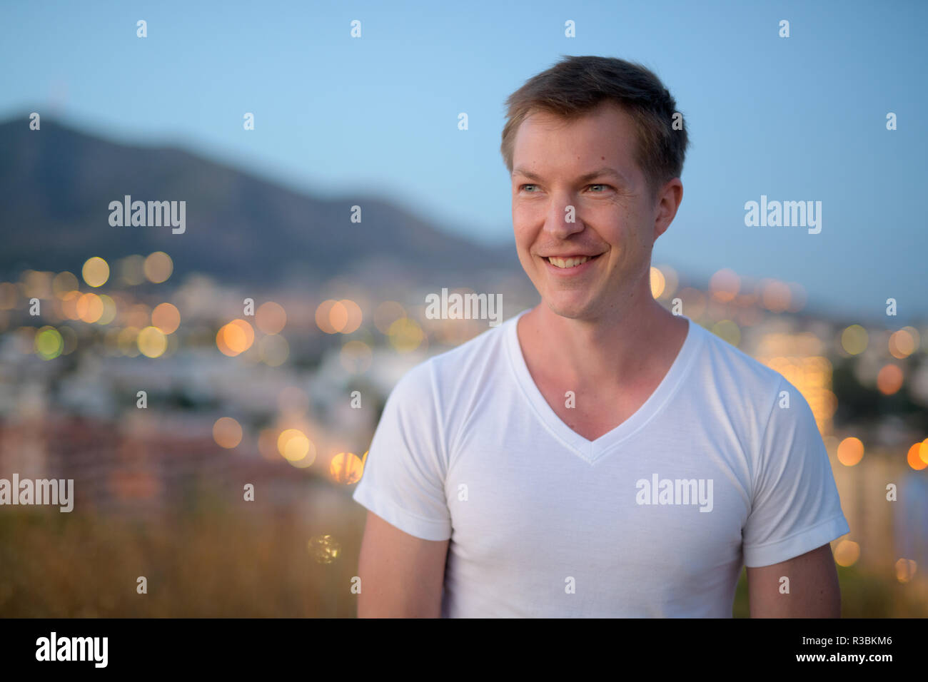 Junge Attraktive touristische Mann lächelnd beim Denken auf dem Hügel Stockfoto