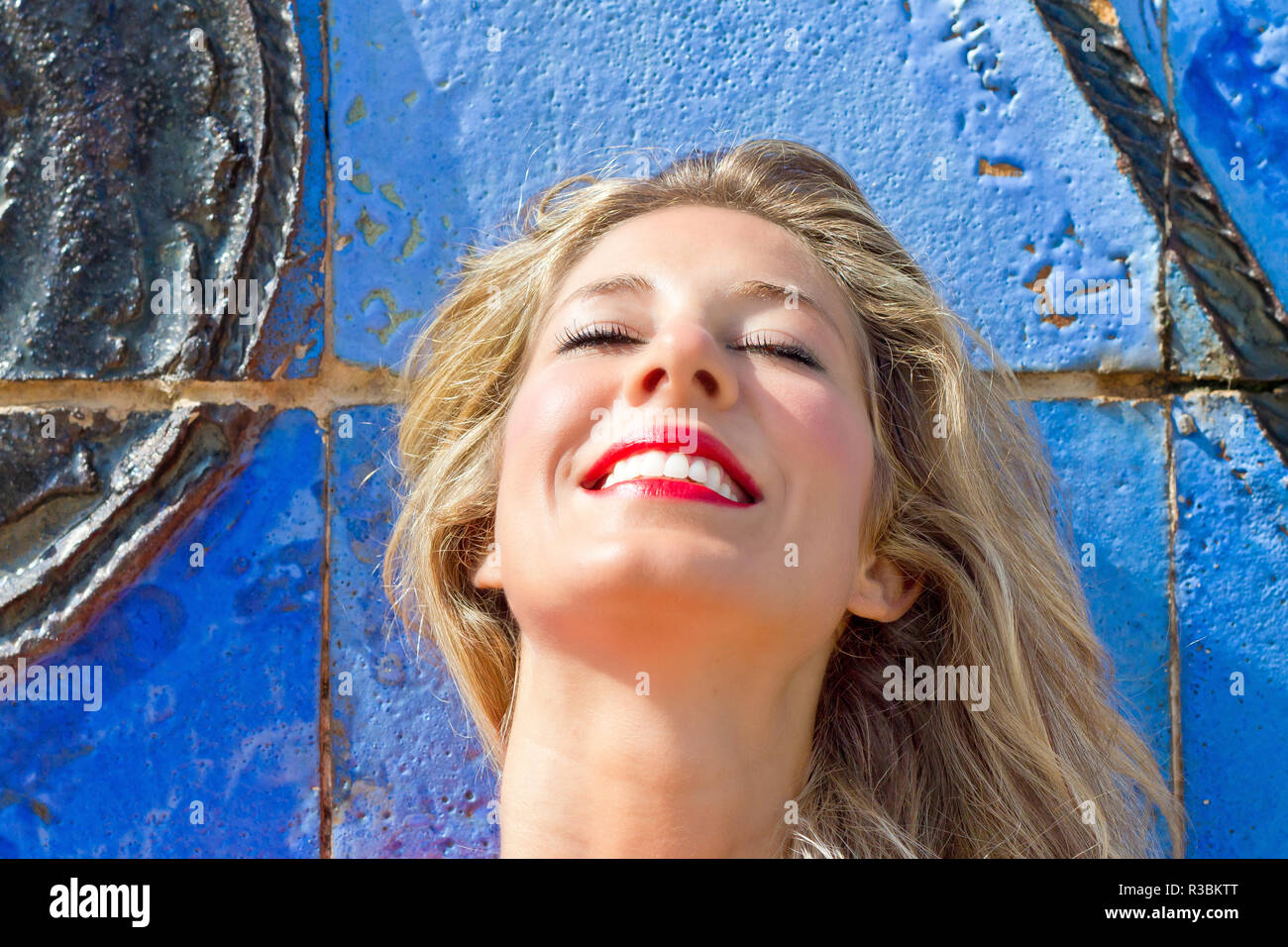 Junge blonde Frau vor einer blauen Wand Stockfoto