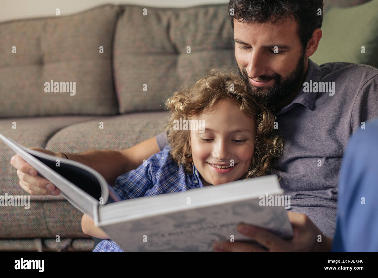 Lächelnde Junge und sein Vater ein Buch lesen zu Hause. Stockfoto