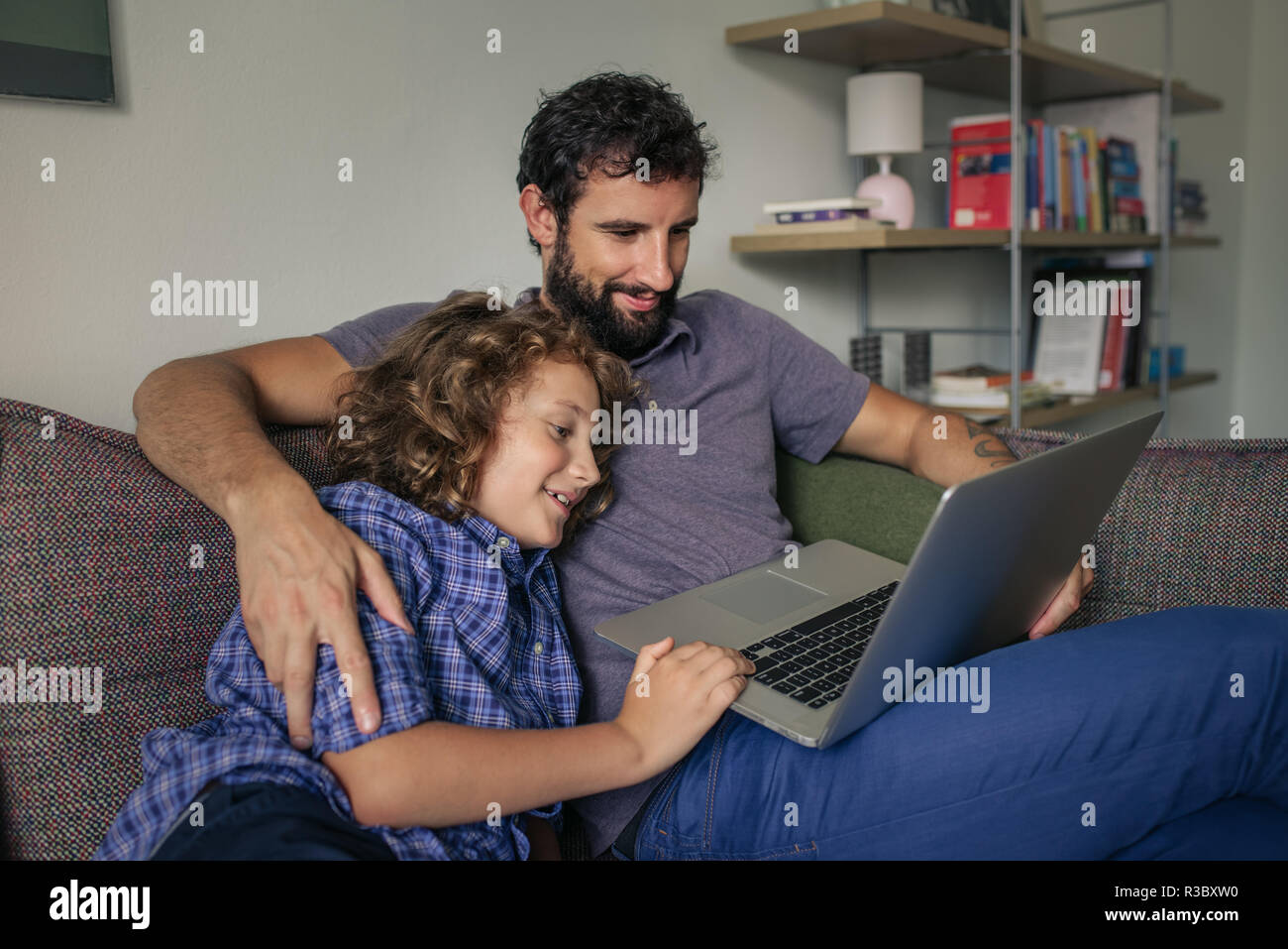 Lächelnde Junge und sein Vater Filme auf einem Laptop Stockfoto