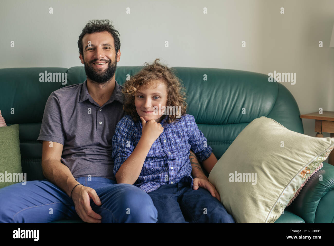 Lächelnd Vater und Sohn sitzen zusammen auf dem Sofa Stockfoto