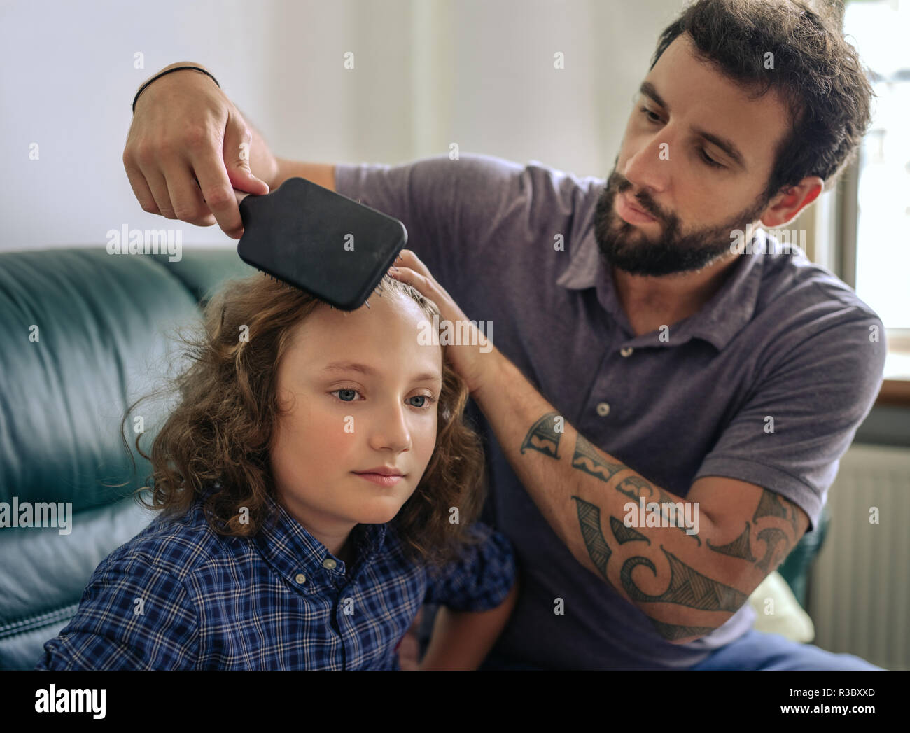 Vater kämmen langes lockiges Haar seines jungen Sohnes zu Hause. Stockfoto