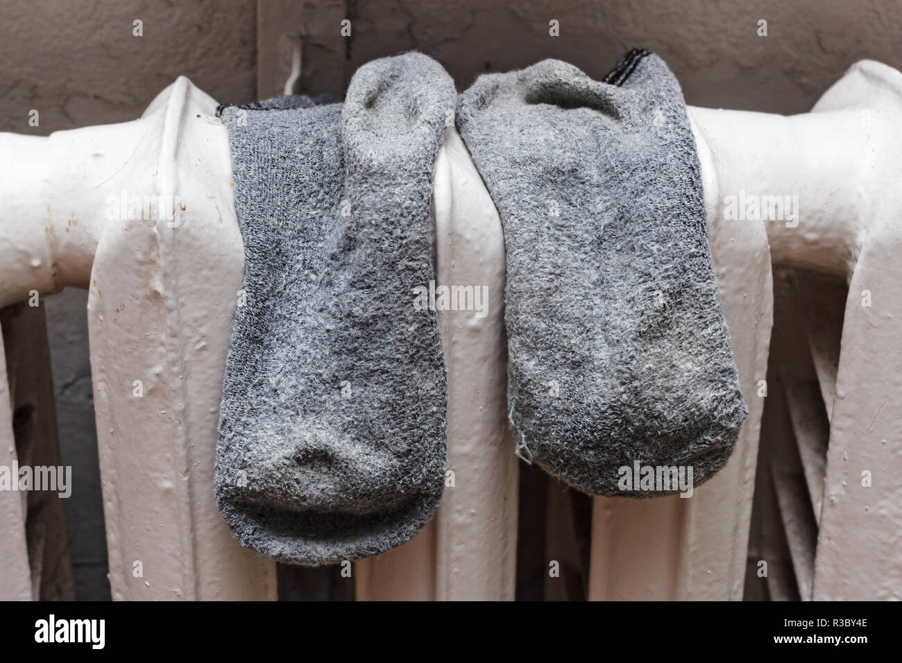 Alte graue Socken zum Trocknen auf Batterie in pro Tag und Zimmer Stockfoto
