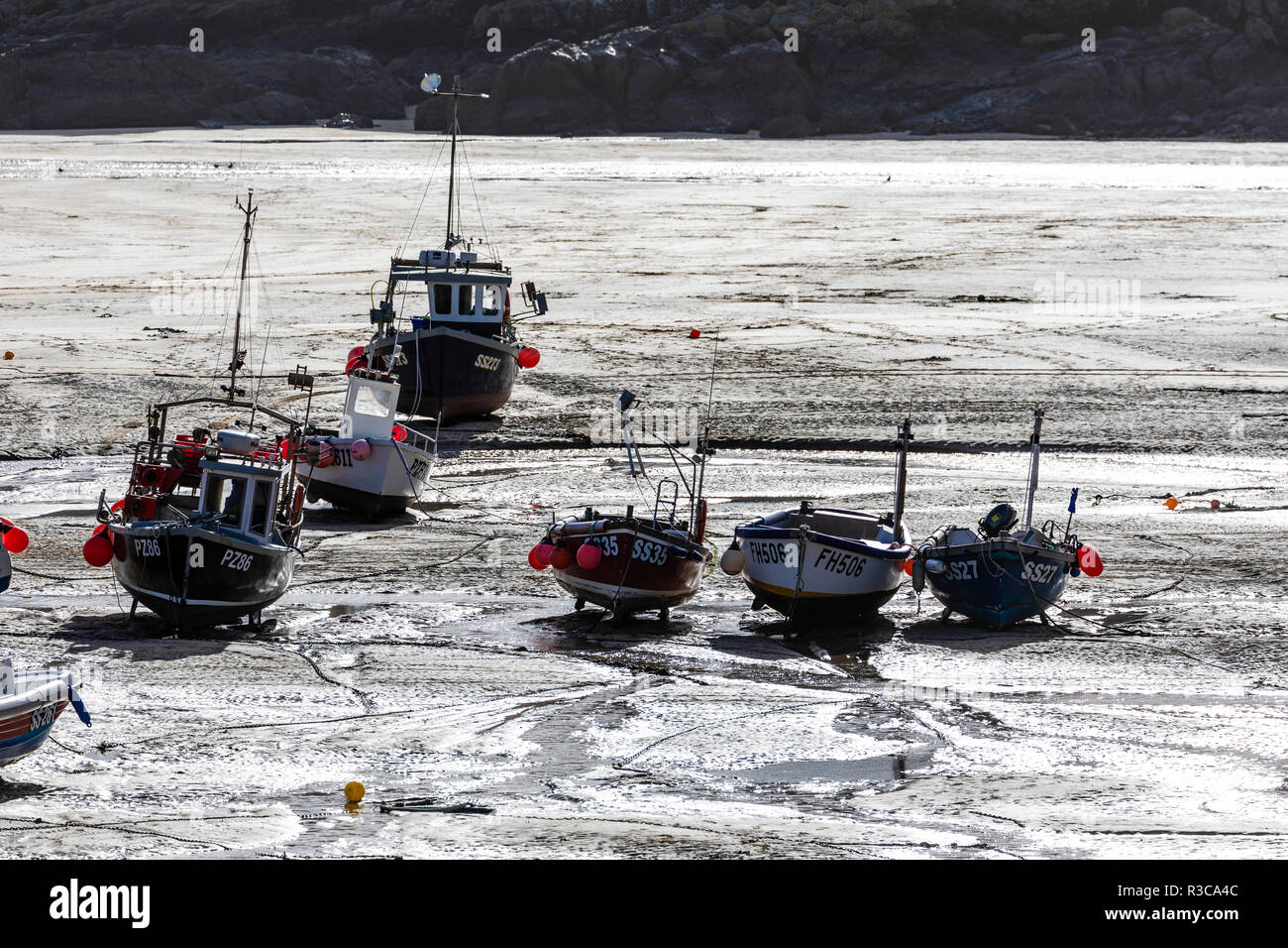 Fischerboote ausgetrocknet ist, im Schutz der Hafen von St Ives, Cornwall und durch die niedrigen Winter Sonne beleuchtet. Stockfoto