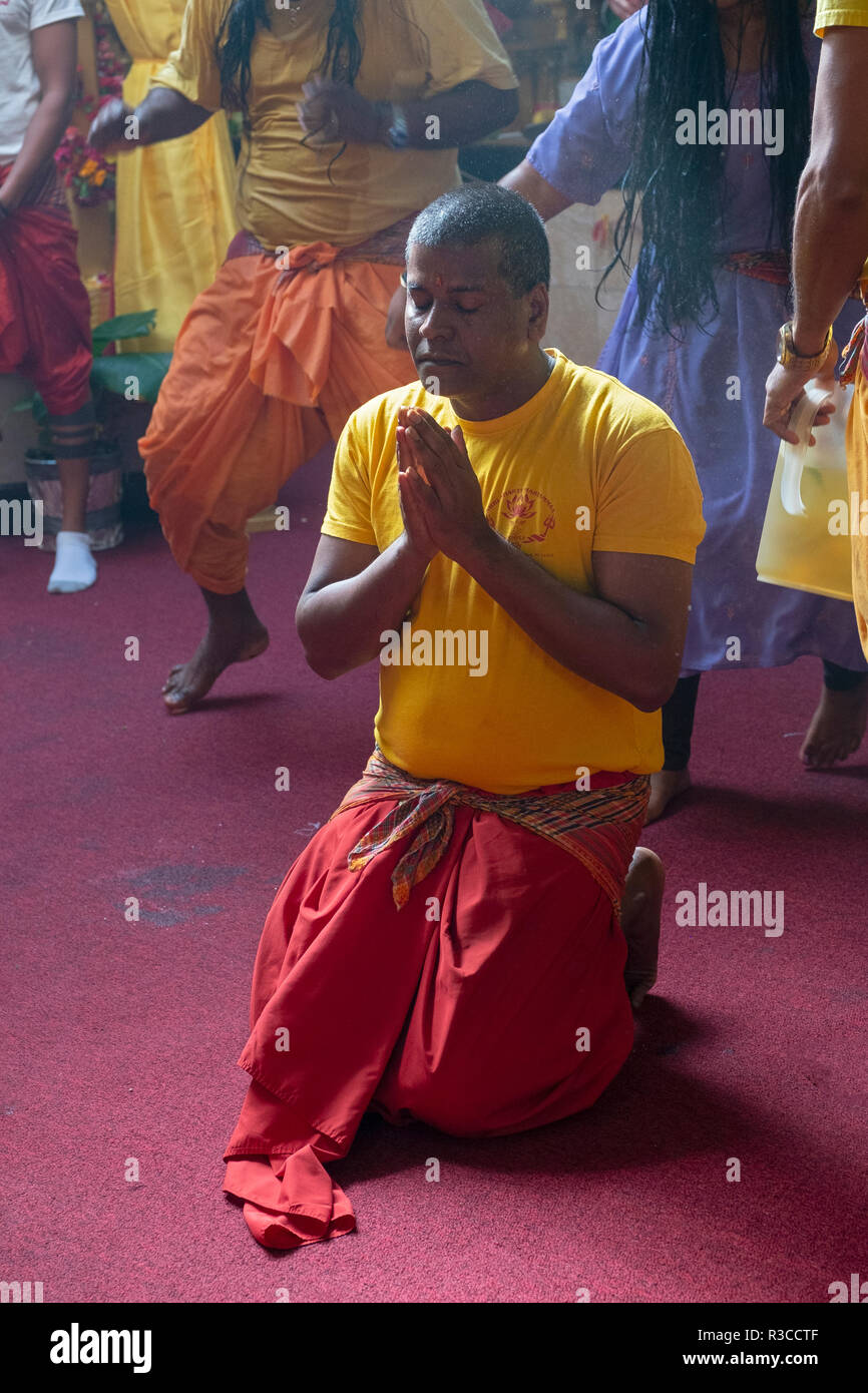 Ein frommer Hindu Verehrer auf seinen Knien mit gefalteten Händen in einem hinduistischen Tempel in Queens, New York City. Stockfoto
