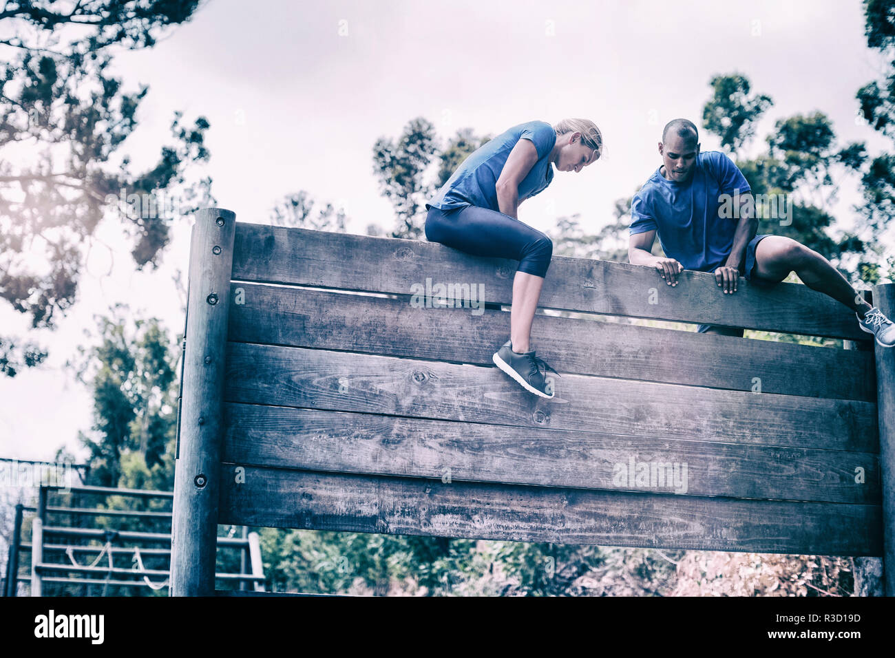 Passen Mann und Frau klettern auf Holz Wand während des Parcours Stockfoto
