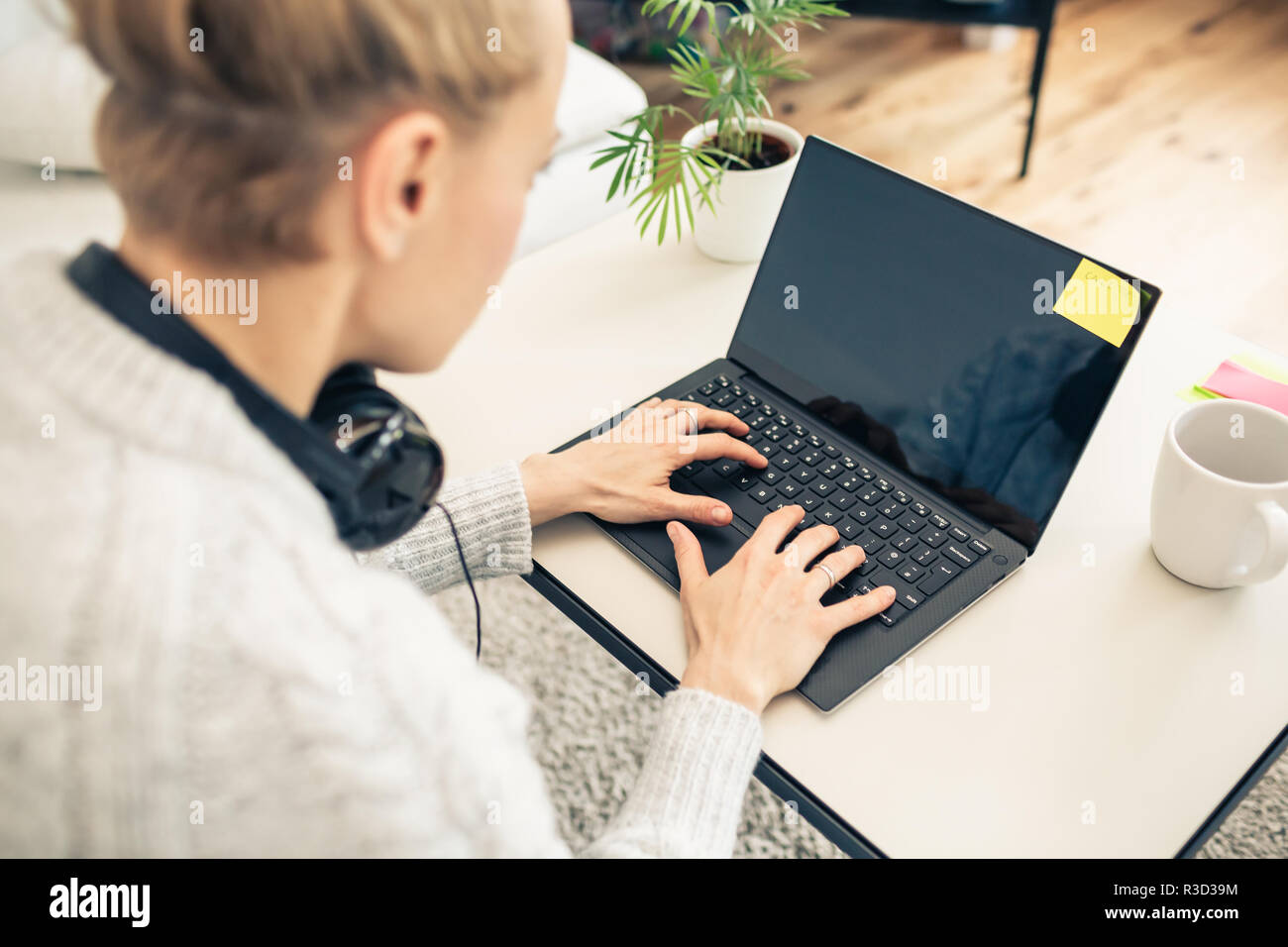 Frau von zu Hause aus arbeiten am Laptop. Home Office von einem warmen gemütlichen Couch. Auf dem Bildschirm. Stockfoto