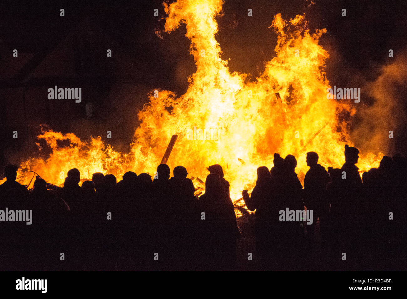 Silhouetten von Menschen, die vor einem großen Lagerfeuer am 5. November in England feiern Stockfoto