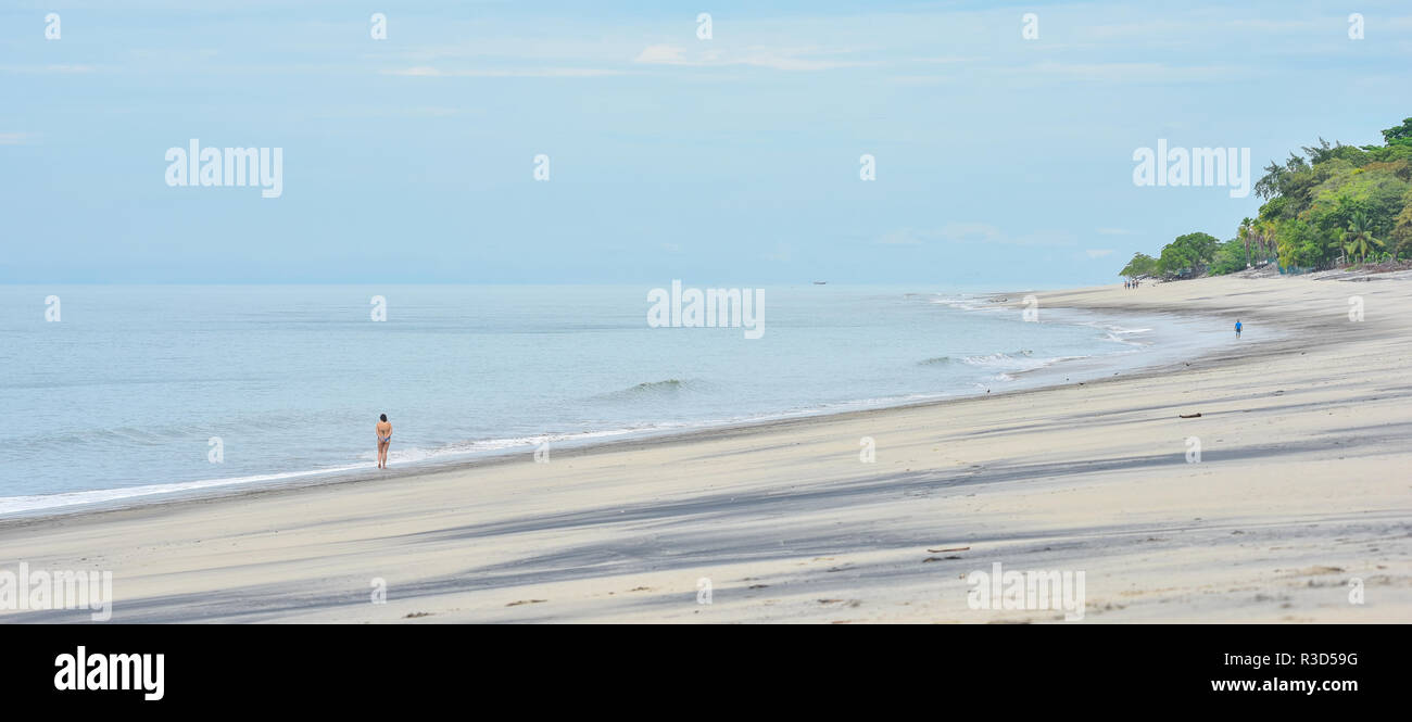 Zwei Menschen in der Ferne Spaziergang entlang getrennt gesehen, auf einer ansonsten leeren Strand bei Ebbe. Stockfoto