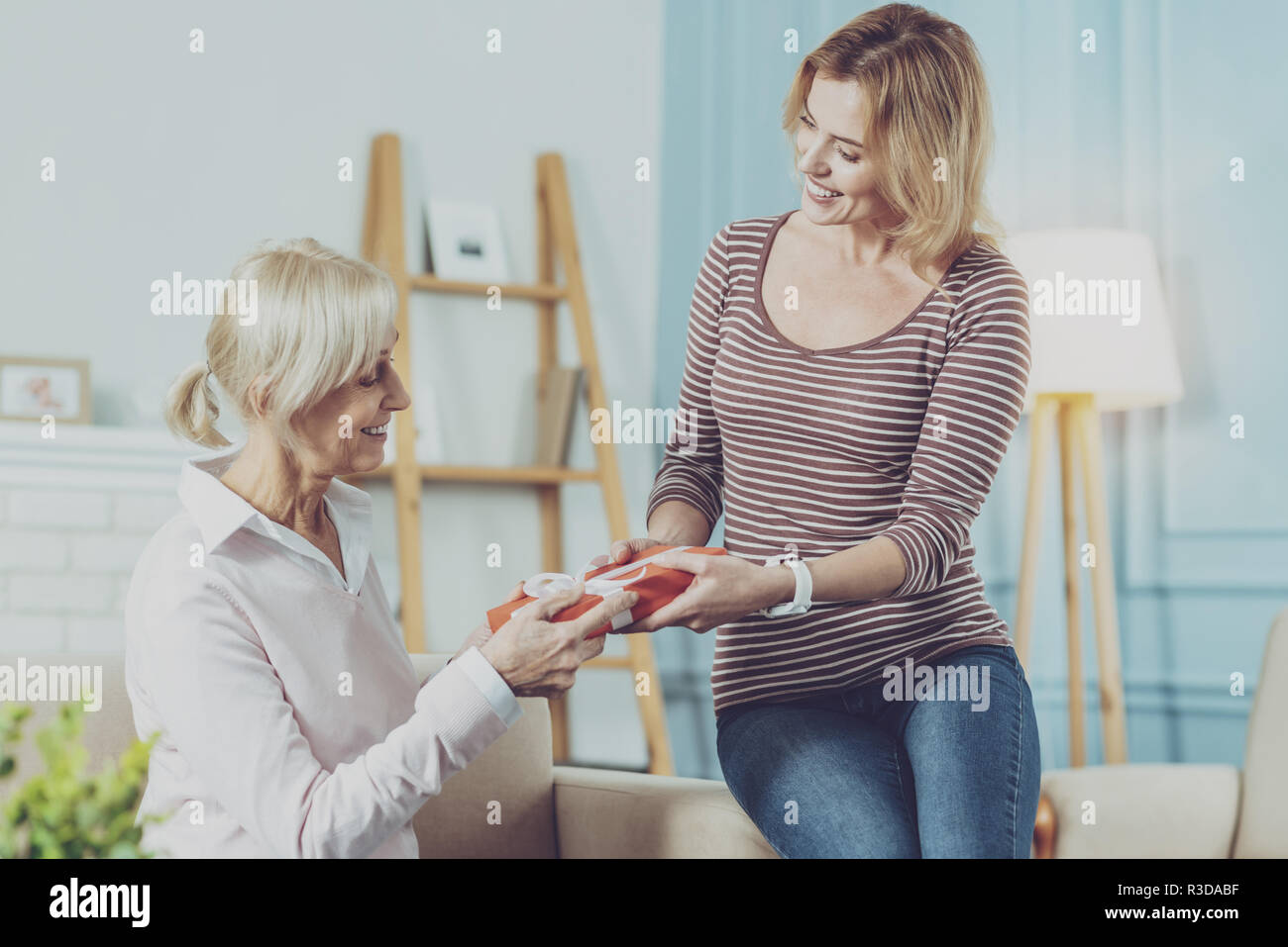 Angenehme Überraschung. Liebevolle ältere Mutter, die ein Geschenk von ihren Jungen schöne Tochter und es während der schönen Zeit bei hom Stockfoto