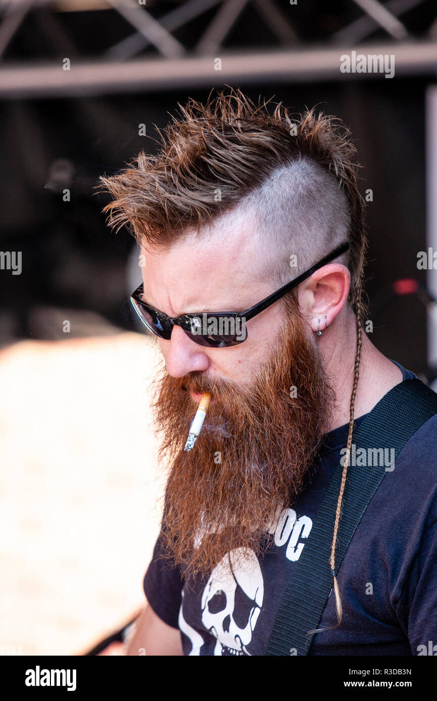 Faversham Hop Festival 2018, Guitch von französischen Rock Folk Band Sur Les Docks. Langen Bart und Brille, Blick nach unten und rauchen eine Zigarette. Stockfoto
