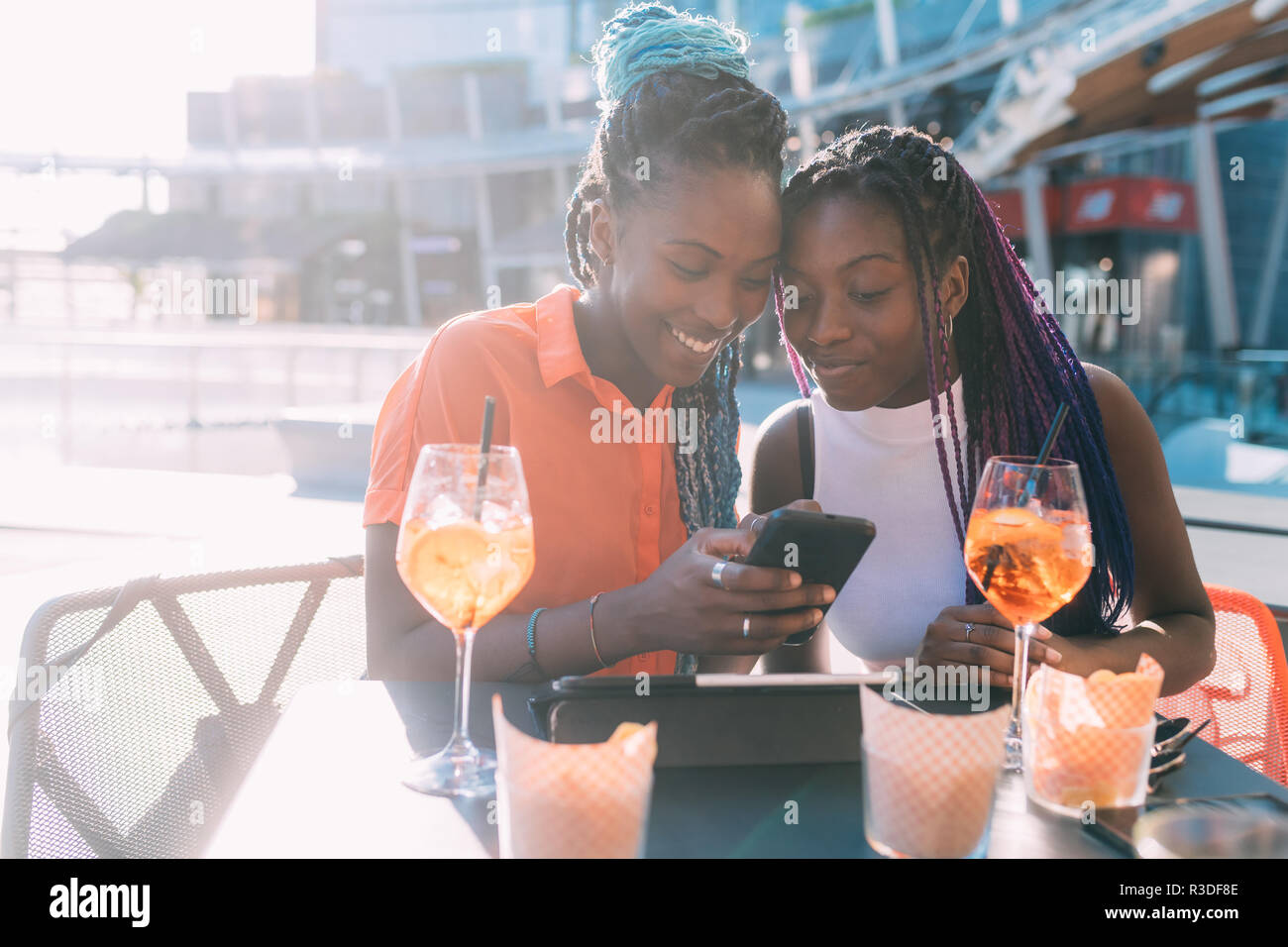 Zwei Frauen Schwestern sitzen Outdoor Bar mit Happy Hour mit smart phone - Geselligkeit, Technologie, entspannende Konzept Stockfoto