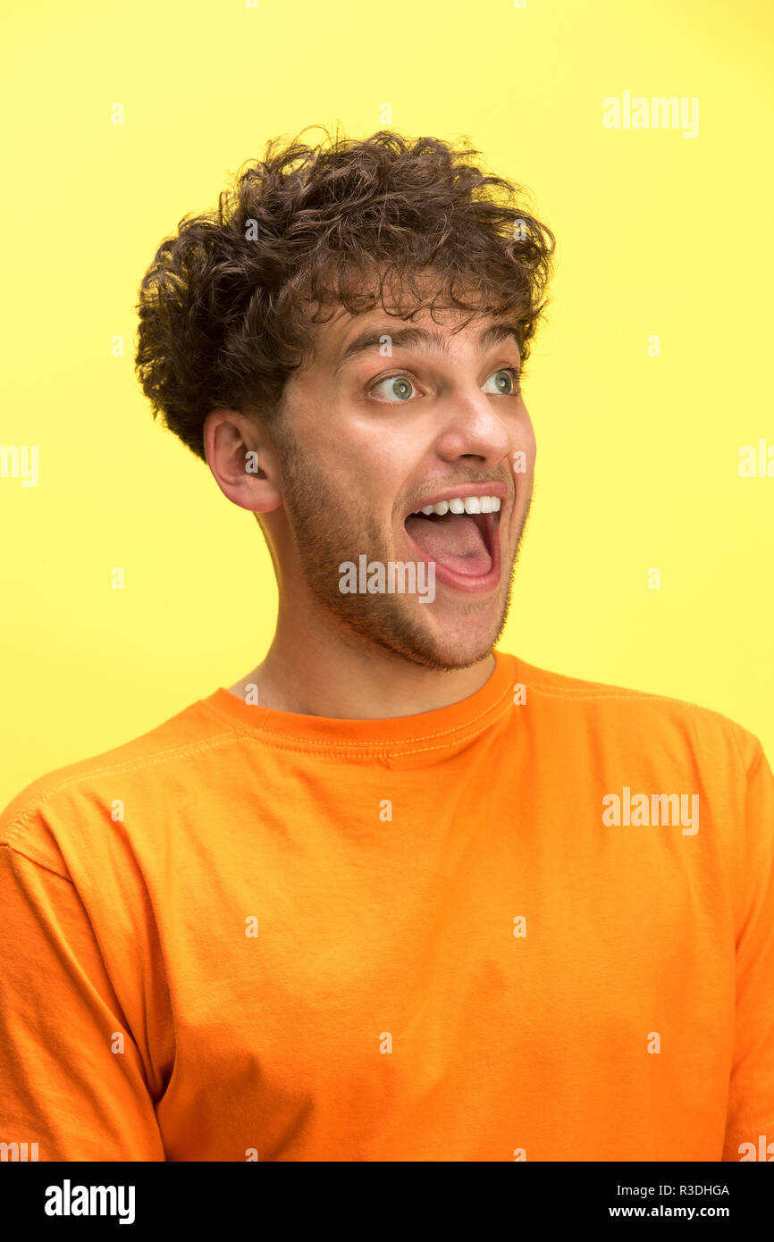 Das überrascht und erstaunt junge Mann schreiend mit offenen Mund auf gelben Hintergrund isoliert. Konzept der Schock Gesicht emotion Stockfoto