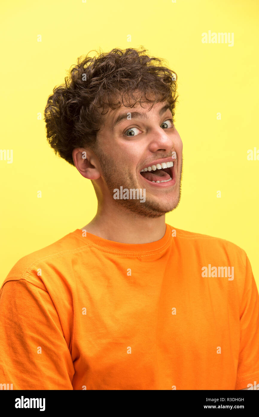 Das überrascht und erstaunt junge Mann schreiend mit offenen Mund auf gelben Hintergrund isoliert. Konzept der Schock Gesicht emotion Stockfoto