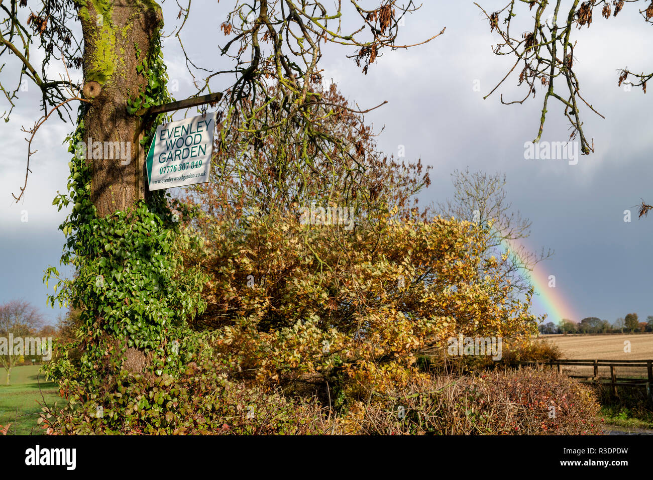 Regenbogen hinter dem Zeichen zu Evenley Holz Garten im Herbst. Evenley, Northamptonshire, England Stockfoto