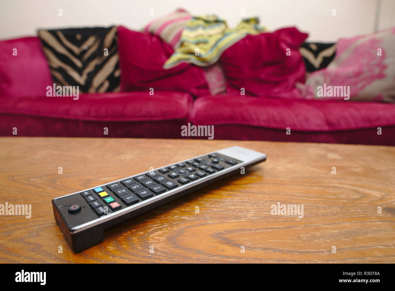TV-Fernbedienung auf Coffe Table vor unordentlich Sofa. Stockfoto
