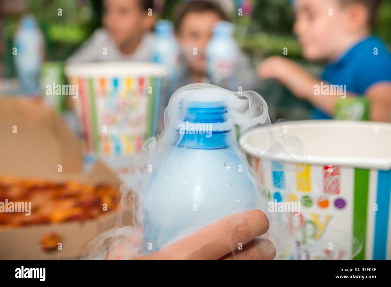 Rauch Effekt aus Kunststoff Flasche Wasser in der Hand auf Geburtstagsfeier verschwommenen Hintergrund. Close Up. Stockfoto