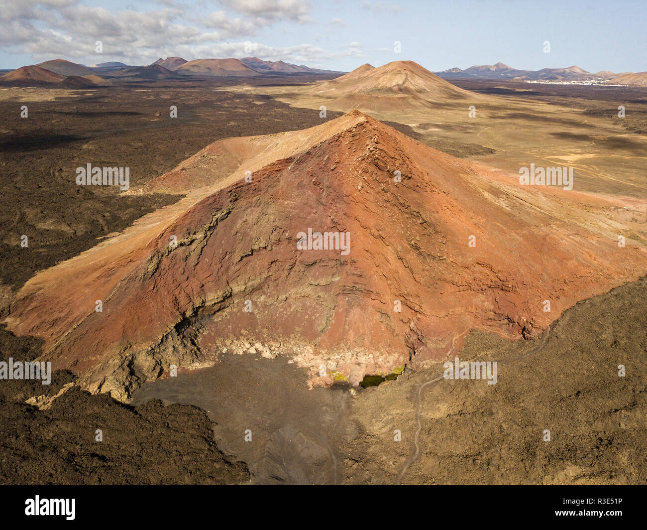 Luftaufnahme der Bermeja Berg von einer intensiv roten Farbe, von lavafeldern umgeben. Lanzarote, Kanarische Inseln, Spanien Stockfoto