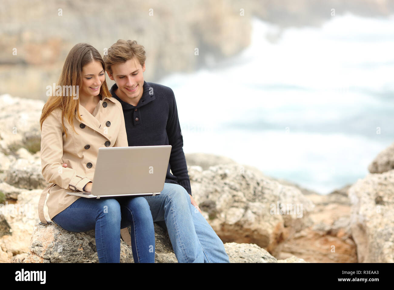 Paar in einem Laptop am Strand im Urlaub Stockfoto
