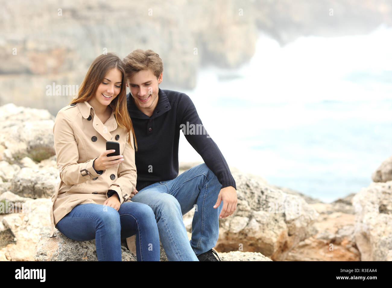 Paar teilen ein smart phone am Strand im Urlaub Stockfoto