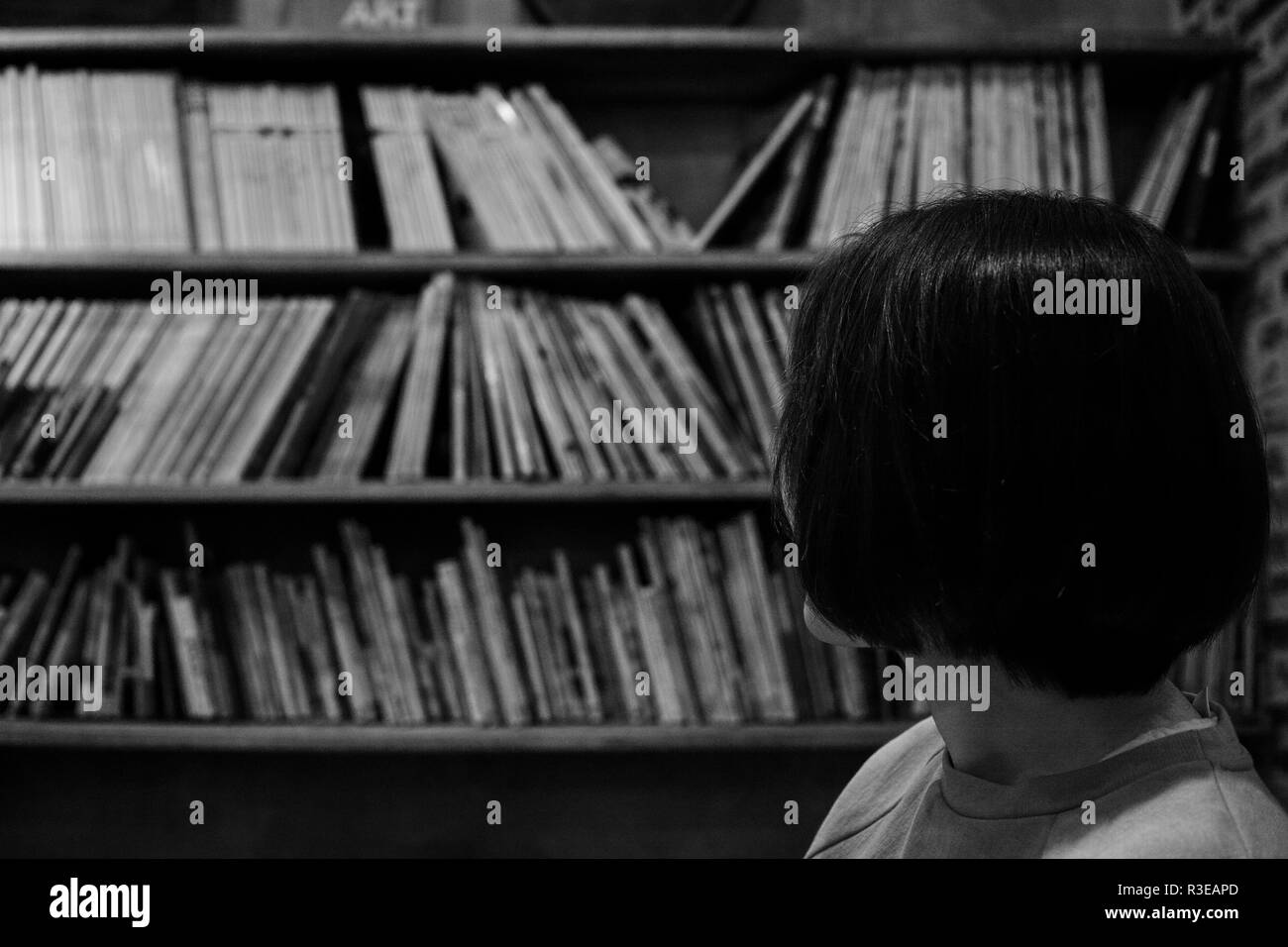 Eine Frau in den Zeilen der Bücher, die auf den Regalen, in Schwarz und Weiß Stockfoto