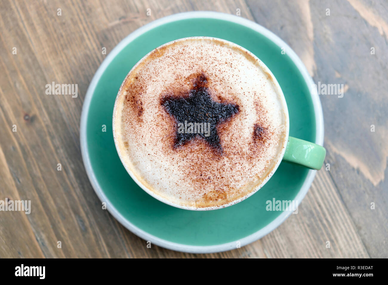 Festliche Tasse Cappuccino mit einem Christmas Star Design von Schokolade bestreut mit aufgeschäumter Milch in eine grüne Tasse und Untertasse UK KATHY DEWITT Stockfoto