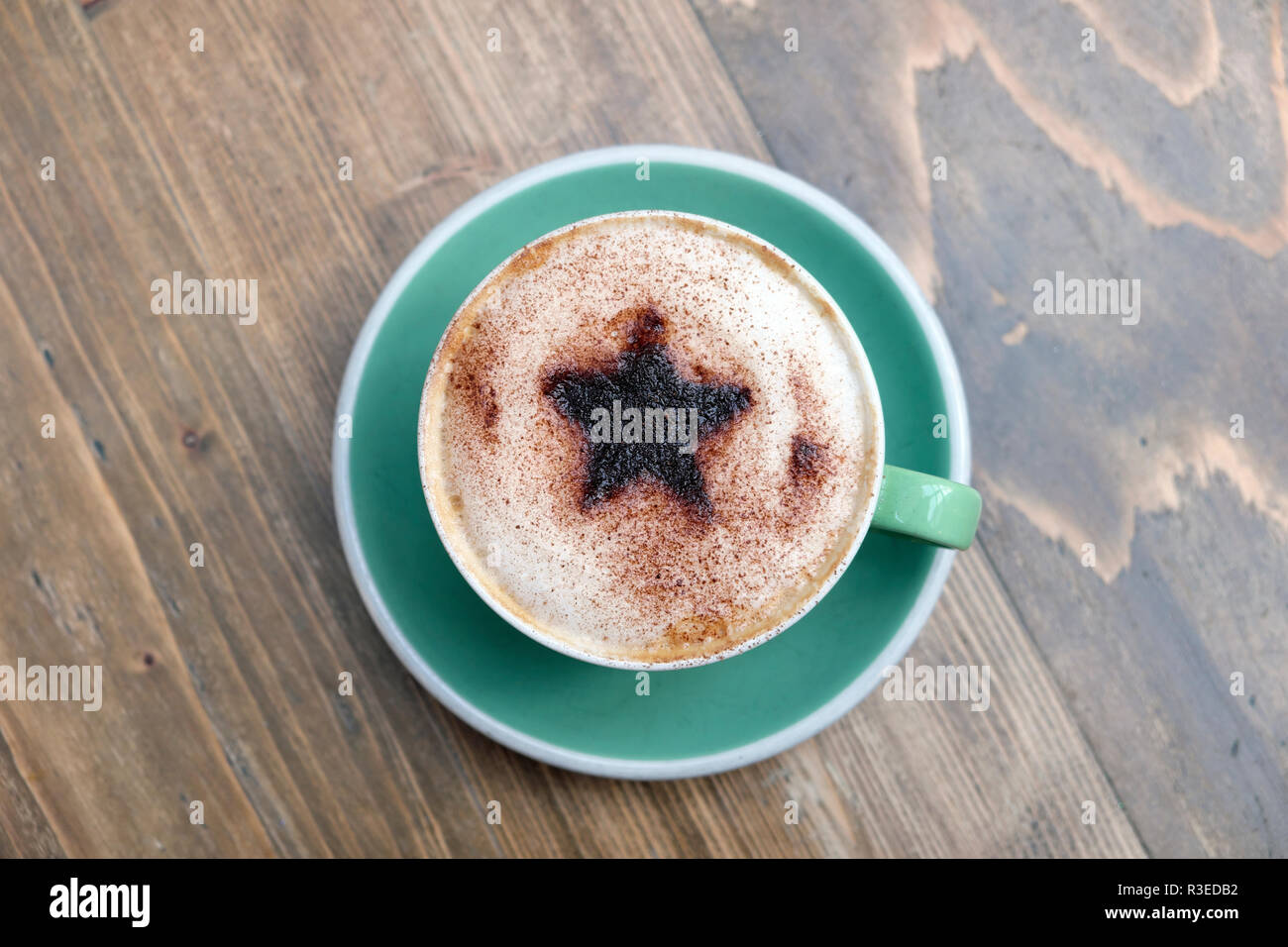 Festliche Tasse Cappuccino mit einem Christmas Star Design von Schokolade bestreut mit aufgeschäumter Milch in eine grüne Tasse und Untertasse UK KATHY DEWITT Stockfoto